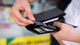 Eine Person steckt eine Bankomat- oder Kreditkarten in ein Geldbrsel.